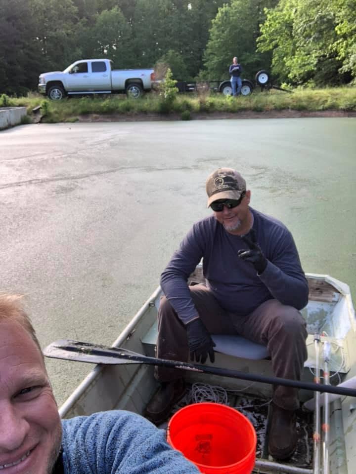 EMS technicians sampling from a boat on a treatment lagoon