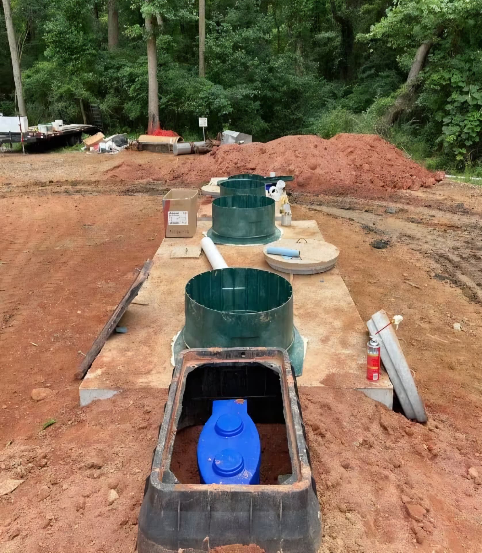 Fiberglass risers and tank lids set on a new concrete pad at an install site